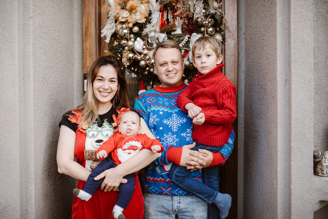 Eltern und Kinder in weihnachtlicher Kleidung vor einer festlich geschmückten Tür.