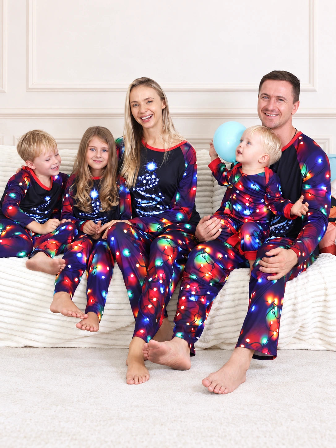 Weihnachtspyjama Unisex – Familie sitzend im dunklen JJF168-Pyjama mit blauem Weihnachtsbaum und buntem Lichterketten-Druck